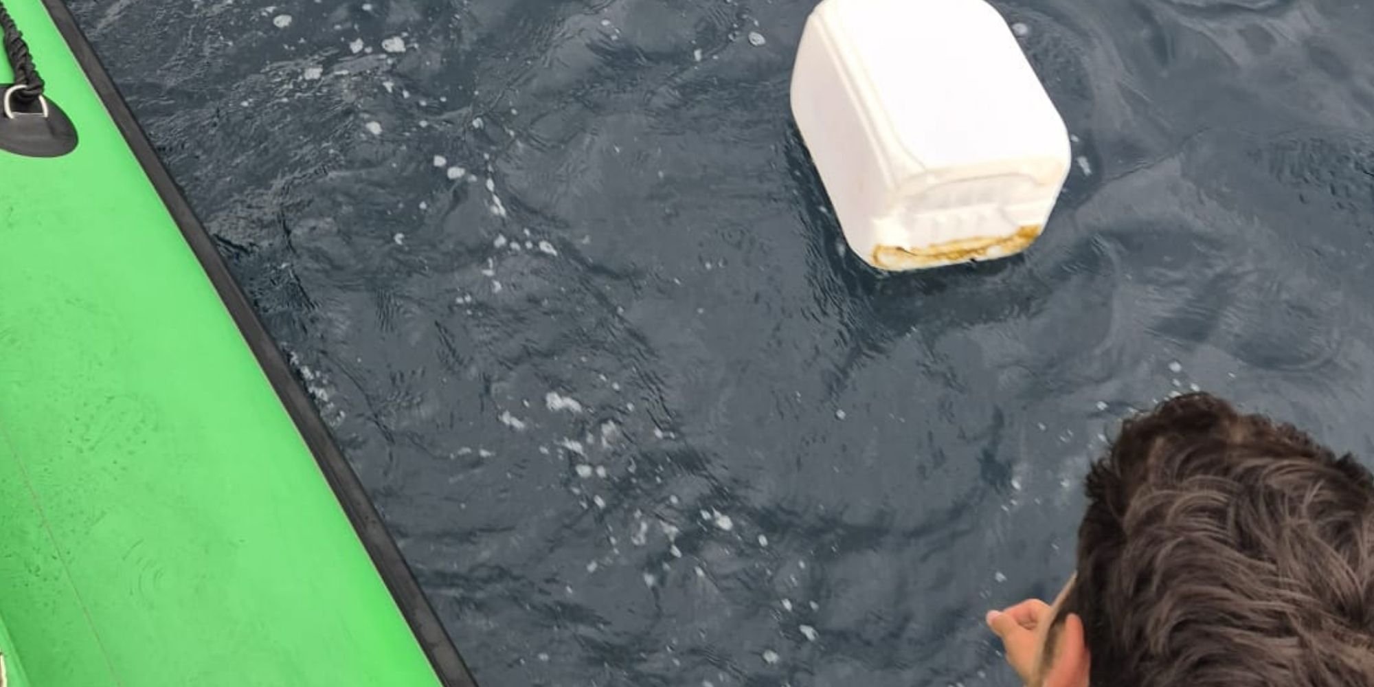 Drijvend plastic afval in zee naast een boot op de Azoren.